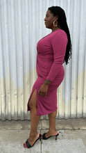 Load image into Gallery viewer, Full-body side view of a size 14 Cushnie berry mauve twist-front long sleeve midi dress with a front slit styled with black kitten heels on a size 14/16 model. The photo was taken outside in natural lighting.