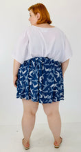 Load image into Gallery viewer, Back view of the size 3 Fashion to Figure x Sarah Rae Vargas crisp white wide-sleeved bodysuit with stretch at the bottom styled with a navy blue and white circle skirt and white slides, on a size 22 model.