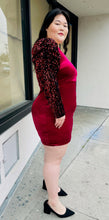 Load image into Gallery viewer, Full-body side view of a red velvet bodycon mini dress with black velvet puff sleeves with red sequins styled with black heels on a size 14/16 model.
