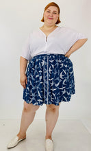 Load image into Gallery viewer, Front view of the size 3 Fashion to Figure x Sarah Rae Vargas crisp white wide-sleeved bodysuit with stretch at the bottom styled with a navy blue and white circle skirt and white slides, on a size 22 model.