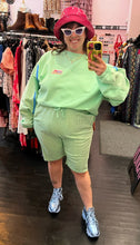 Load image into Gallery viewer, Additional full-body front view of a size XXL Les Benjamins designer two piece pastel green biking set from the "Seoul to Busan" collection, styled with blue sneakers and a pink bucket hat on a size 14/16 model.