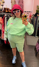 Load image into Gallery viewer, Full-body front view of a size XXL Les Benjamins designer two piece pastel green biking set from the "Seoul to Busan" collection, styled with blue sneakers and a pink bucket hat on a size 14/16 model.