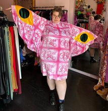 Load image into Gallery viewer, Full-body front view showing off the length and span of the bell sleeves of a size 4XL Fashion Brand Company pink month mini dress with "Jewish Girls" cursive all-over pattern styled with black combat boots on a size 24 model. The photo is taken inside in front of a window, combining natural light and overhead lighting.