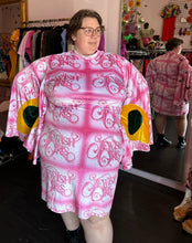 Load image into Gallery viewer, Front view of a size 4XL Fashion Brand Company pink month mini dress with "Jewish Girls" cursive all-over pattern styled with black combat boots on a size 24 model. The photo is taken inside in front of a window, combining natural light and overhead lighting.