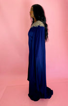 Load image into Gallery viewer, Full-body side view of a size 16 Marchesa royal purple silky caped floor-length gown with embroidered and beaded neckline and cape on a size 12 model. The photo was taken inside under photography lighting.
