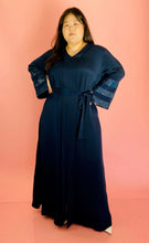 Load image into Gallery viewer, Full-body front view of a size XXL Sachin &amp; Babi deep navy blue silky faux-wrap gown with long sleeves and sequin stripes on a size 14/16 model. The photo was taken indoors under studio lighting.
