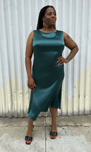 Load image into Gallery viewer, Full-body front view of a size 12/14 Henning deep teal silky sleeveless midi dress styled with black kitten heels on a size 14/16 model. The photo was taken outside in natural lighting.
