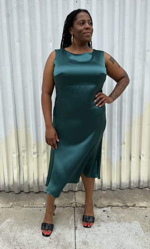 Full-body front view of a size 12/14 Henning deep teal silky sleeveless midi dress styled with black kitten heels on a size 14/16 model. The photo was taken outside in natural lighting.