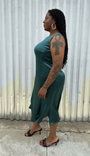 Load image into Gallery viewer, Full-body side view of a size 12/14 Henning deep teal silky sleeveless midi dress styled with black kitten heels on a size 14/16 model. The photo was taken outside in natural lighting.
