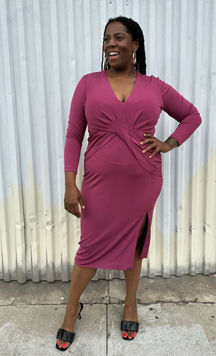 Full-body front view of a size 14 Cushnie berry mauve twist-front long sleeve midi dress with a front slit styled with black kitten heels on a size 14/16 model. The photo was taken outside in natural lighting.