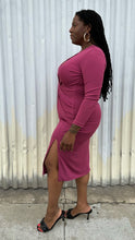 Load image into Gallery viewer, Full-body side view of a size 14 Cushnie berry mauve twist-front long sleeve midi dress with a front slit styled with black kitten heels on a size 14/16 model. The photo was taken outside in natural lighting.
