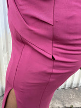 Load image into Gallery viewer, Close up photo of the small hole at the seam of a size 14 Cushnie berry mauve twist-front long sleeve midi dress with a front slit styled with black kitten heels on a size 14/16 model. This garment is sold AS IS.
