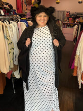 Load image into Gallery viewer, Front view of a size 1/2X Leg Avenue black bat costume hoodie with bat wing, connected sleeves and fuzzy ears on the hood, styled unzipped, open over a white and black polka dot dress on a size 14/16 model.
