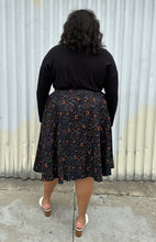 Load image into Gallery viewer, Full-body back view of a size 4X (fits like 2X) Banned Retro black maxi skirt with orange, purple, and white mixed Halloween pattern featuring cats with witch hats styled with a black long sleeve and white mules on a size 18/20 model. The photo was taken outside in natural lighitng.
