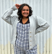 Load image into Gallery viewer, Front view of a size 22/24 Eloquii light gray cardigan with pearl &amp; gold buttons styled open over a blue &amp; white plaid jumpsuit on a size 18/20 model. The photo was taken outside in natural lighting.
