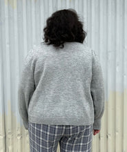 Load image into Gallery viewer, Back view of a size 22/24 Eloquii light gray cardigan with pearl &amp; gold buttons styled over a blue &amp; white plaid jumpsuit on a size 18/20 model. The photo was taken outside in natural lighting.
