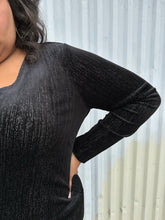 Load image into Gallery viewer, Closer view of the metallic threading of a size 18/20 Eloquii black velvet long sleeve v-neck top with silver metallic threading throughout on a size 18/20 model. The photo was taken outside in natural lighting.
