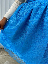 Load image into Gallery viewer, Close up view of the sheer lace overlay of a size 1/2X Beauciel bright baby blue circle skirt with lace overlay styled with a cream sweater on a size 18/20 model. The photo was taken outside in natural lighting.
