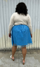 Load image into Gallery viewer, Full-body back view of a size 1/2X Beauciel bright baby blue circle skirt with lace overlay styled with a cream sweater and white mules on a size 18/20 model. The photo was taken outside in natural lighting.

