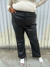 Load image into Gallery viewer, Front view of a size 24 (fits like 20/22) Eloquii black pleather straight leg pants styled with a cream turtleneck and white mules on a size 18/20 model. The photo was taken outside in natural lighting.
