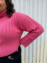 Load image into Gallery viewer, Closer view of the ribbing and turtleneck of a size 18/20 Eloquii bubblegum pink ribbed turtleneck cropped sweater styled over a dark wash denim trouser on a size 18/20 model The photo was taken outside in natural lighting.
