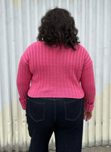 Load image into Gallery viewer, Back view of a size 18/20 Eloquii bubblegum pink ribbed turtleneck cropped sweater styled over a dark wash denim trouser on a size 18/20 model The photo was taken outside in natural lighting.

