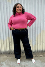 Load image into Gallery viewer, Full-body front view of a pair of size 20 DC Jeans dark wash wide leg denim styled with a bubblegum pink cropped sweater and white mules on a size 18/20 model. The photo was taken outside in natural lighting.
