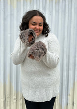 Load image into Gallery viewer, Front view focusing on the faux fur cuffs of a size 18/20 Lane Bryant x Girl with Curves collab gray ribbed longline turtlneck sweater with brown faux fur cuffs styled with dark wash denim on a size 18/20 model. The photo was taken outside in natural lighting.
