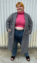 Load image into Gallery viewer, Full-body front view of a size 3X Nilli Lotan x Target black and white gingham double breasted longline peacoat styled open over a pink sweater, medium wash denim, and black slides on a size 22/24 model. The photo was taken outside in natural lighting.

