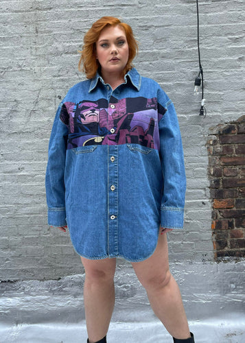 Front view of a size XL Lanvin painted Batman denim button-up styled closed like a mini dress on a size 18 model. The photo is taken outside in natural lighting.