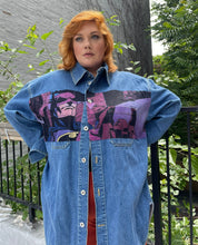 Load image into Gallery viewer, Front view of a size XL Lanvin painted Batman denim button-up styled half-closed over red shorts a size 18 model. The photo is taken outside in natural lighting.
