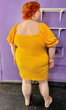 Load image into Gallery viewer, Full-body back view of a size 24 Wednesday&#39;s Girl golden yellow textured off-shoulder puff sleeve mini dress with sweetheart neckline styled with tan sandals on a size 22/24 model. The photo was taken inside in fluorescent and natural lighting.
