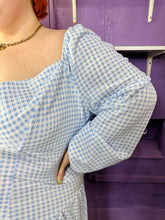 Load image into Gallery viewer, Close up view of the puff sleeves of a size 24 ASOS baby blue and white gingham off-shoulder pointed waistline mini dress on a size 22/24 model. The photo was taken inside in fluorescent and natural lighting.
