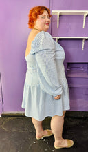 Load image into Gallery viewer, Full-body side view of a size 24 ASOS baby blue and white gingham off-shoulder pointed waistline mini dress on a size 22/24 model. The photo was taken inside in fluorescent and natural lighting.
