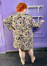 Load image into Gallery viewer, Full-body back view of a size 3 Torrid light tan, orange, purple, and black floral crochet embroidered detail 70s inspired long sleeve midi dress on a size 22/24 model. The photo was taken inside in flourescent and natural lighting.

