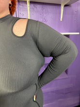 Load image into Gallery viewer, Close up view of the shoulder cut out and all-over ribbing of a size 3X Finesse dark gray ribbed long sleeve midi dress with a shoulder cut out, two front slits, and contrast stitching details on a size 22/24 model. The photo was taken inside in flourescent and natural lighting.
