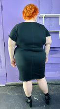 Load image into Gallery viewer, Full-body back view of a size 3 Torrid black sleeveless textured shift midi dress styled with black patent leather boots on a size 22/24 model. The photo was taken inside under flourescent and natural lighting.
