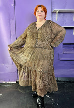 Load image into Gallery viewer, Additional full-body front view of a size 4X H&amp;M dark &amp; light brown and cream floral and paisley tiered maxi dress styled with black patent leather boots on a size 22/24 model. The photo was taken inside under flourescent and natural lighitng.

