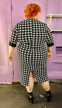 Load image into Gallery viewer, Full-body back view of a size 2X SHEIN black &amp; white houndstooth plaid midi dress with three-quarter sleeves and gold non-functional buttons styled with black boots on a size 22/24 model. The photo was taken inside under flourescent and natural lighting.
