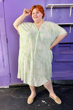 Load image into Gallery viewer, Full-body front view of a size XXL (fits up to 24 comfy) H&amp;M light green and white acid wash tie dye caftan styled with tan slides on a size 22/24 model. The photo was taken inside under fluorescent and natural lighting.
