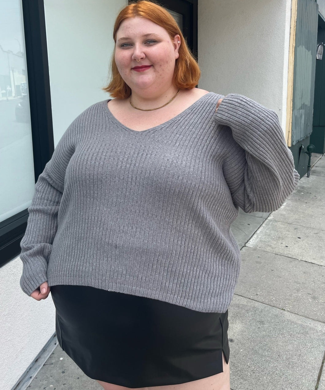Front view of a a size 4X Wild Fable gray-brown v-neck knit sweater styled over a pleather mini skirt on a size 22/24 model. The photo is taken outside in natural lighting.
