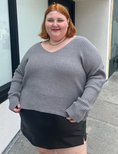 Load image into Gallery viewer, Additional front view of a a size 4X Wild Fable gray-brown v-neck knit sweater styled over a pleather mini skirt on a size 22/24 model. The photo is taken outside in natural lighting.
