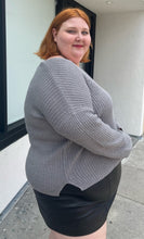 Load image into Gallery viewer, Side view of a a size 4X Wild Fable gray-brown v-neck knit sweater styled over a pleather mini skirt on a size 22/24 model. The photo is taken outside in natural lighting.
