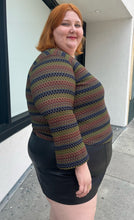 Load image into Gallery viewer, Side view of a size 22/24 vintage Venezia textured green, blue, and brown striped long sleeve top styled over a black pleater mini skirt on a size 22/24 model. The photo is taken outside in natural lighting.
