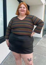 Load image into Gallery viewer, Front view of a size 22/24 vintage Venezia textured green, blue, and brown striped long sleeve top styled tucked into a black pleater mini skirt on a size 22/24 model. The photo is taken outside in natural lighting.
