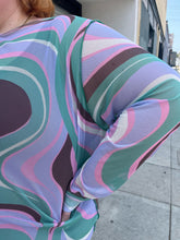 Load image into Gallery viewer, Close up view of the sheer-leaning mesh swirly pattern of a size 26 ASOS light purple, pink, brown, and green swirl pattern long sleeve mesh mini dress on a size 22/24 model. The photo is taken outside in natural lighting.
