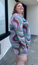 Load image into Gallery viewer, Side view of a size 26 ASOS light purple, pink, brown, and green swirl pattern long sleeve mesh mini dress on a size 22/24 model. The photo is taken outside in natural lighting.
