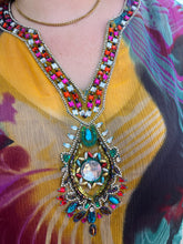 Load image into Gallery viewer, Close up view of the beads and jewels at the neckline of a size 20-24 purple, yellow, blue, pink, and black abstract pattern 100% silk blouse with beaded and bejeweled neckline on a size 22/24 model. The photo is taken outside in natural lighting.
