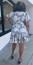 Load image into Gallery viewer, Full-body back view of a size 3X Fashion Nova light blue, white, and purple floral wrap mini dress with matching belt and puff sleeves styled with blue heels on a size 16/18 model.
