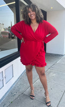 Load image into Gallery viewer, Additional full-body front view of a size 22 Pretty Little Thing red wrap mini dress with ruffles and tulip hem styled with black heels on a size 16/18 model. The photo is taken outside in natural lighting.
